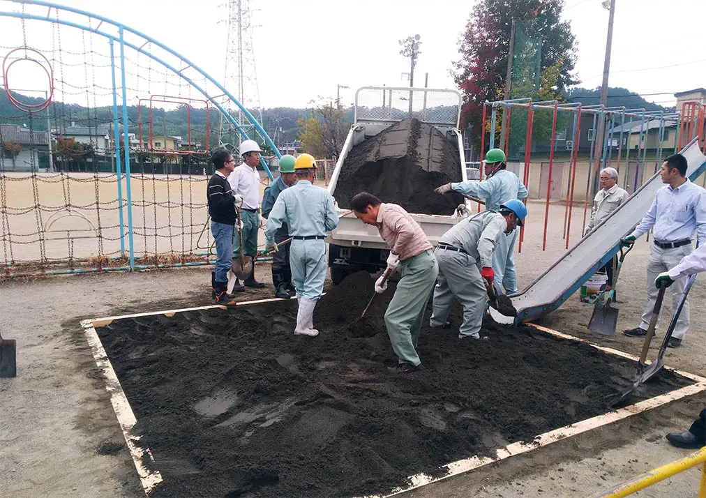 小学校の砂場へ砂を入れる作業の様子